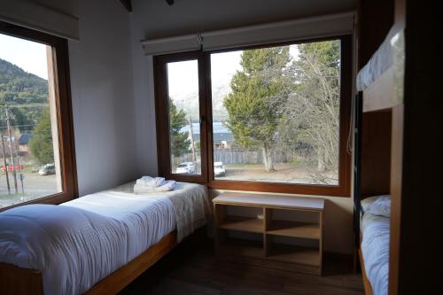 サン・カルロス・デ・バリローチェにあるGuti Andino Hostel Boutiqueのベッドと大きな窓のある寝室