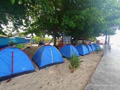 a row of blue tents on the beach at Three Ken Homestay & Cafe in Manado