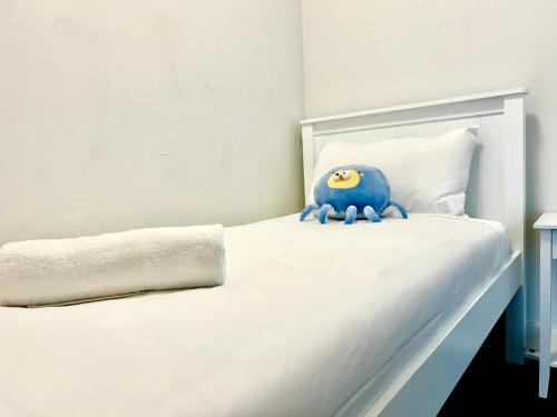 a white bed with a blue toy on it at Green View 2B2B Olympic Park in Sydney