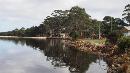 a body of water with trees in the background at Strahan Retreat Holiday Park in Strahan