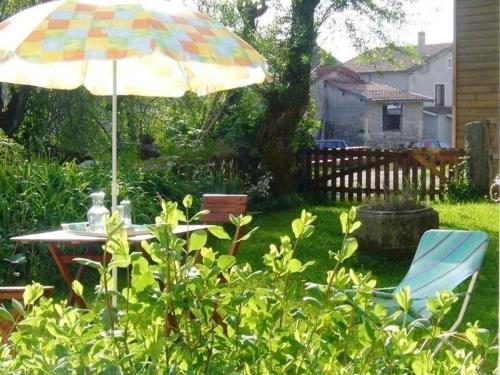 a table and chairs and an umbrella in a yard at Gîte chaleureux entre festivals, nature et confort avec wifi à Jullianges - FR-1-582-237 in Jullianges