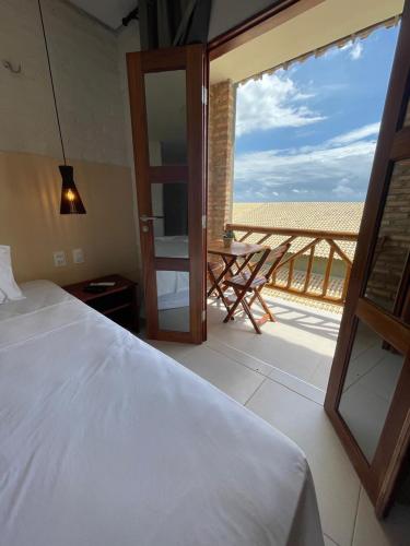 トライリにあるHotel das Marésのベッドルーム1室(ベッド1台付)、バルコニー(テーブル付)
