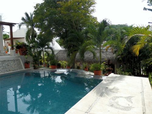 a swimming pool in a yard with palm trees at Casa Blanca in Santa Cruz Huatulco