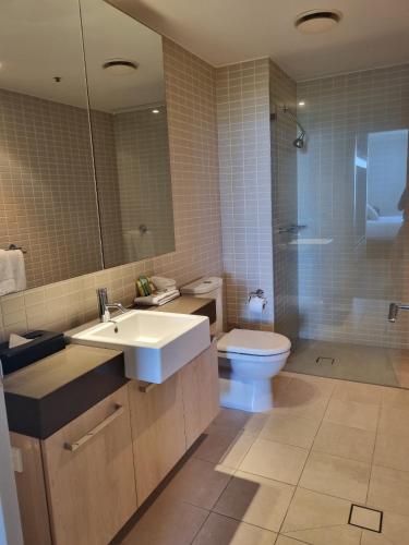 a bathroom with a sink and a toilet and a mirror at Cairns Private Apartments in Cairns