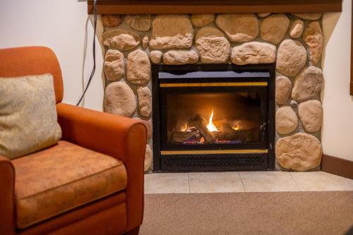 a fireplace in a living room with a couch and a chair at Silver Rock Condominiums by Fernie Central Reservations in Fernie