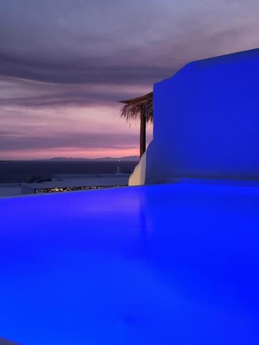 a blue building with a palm tree in the background at ELLI TROPiCAL LUXURY SUITES SUNSET-INFINITY POOL- SEA SIDE-NEAR CENTER PARKING in Mikonos