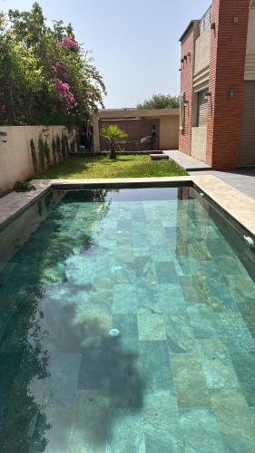 una piscina con azulejos azules en un patio en Petit Palm, en El Rhechat