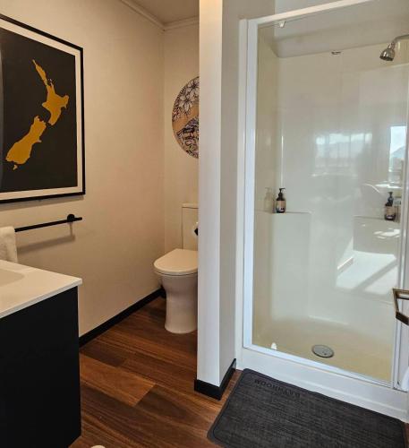 a bathroom with a toilet and a glass shower at Wild Kea Lodge Franz Josef in Franz Josef