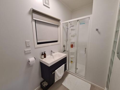 a white bathroom with a sink and a shower at Lexs Guesthouse in Gisborne