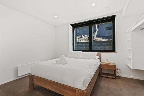 a white bedroom with a bed and a window at Moritz 1 in Mount Hotham