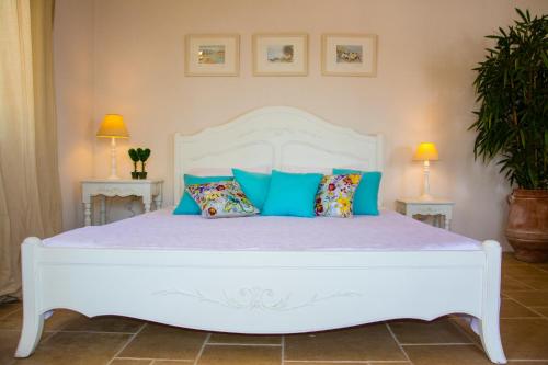 a white bed with blue pillows in a bedroom at Ideales Resort in Trapezaki