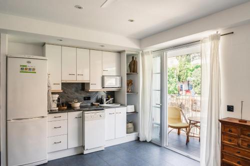 a kitchen with white cabinets and a sliding glass door at ONA House Begur in Sa-Riera
