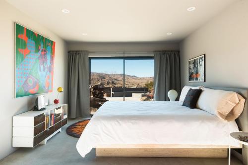 a bedroom with a white bed and a large window at Heaven's Door By The Cohost Company in Pioneertown