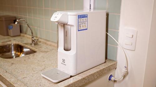 a white appliance on a counter next to a sink at FLAT NOVO e ACONCHEGANTE in Ribeirão Preto