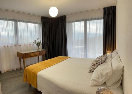 a bedroom with a bed and a desk and windows at Serradinho Country House 