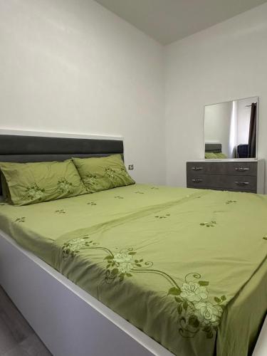 a bed with a green comforter and a mirror at Sol & Sea Apartments 2 in Shëngjin