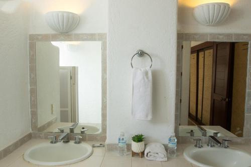 une salle de bain avec deux lavabos et deux miroirs dans l'établissement Apt with Jacuzzi Ixtapa Zihuatanejo 3 BR, à Ixtapa