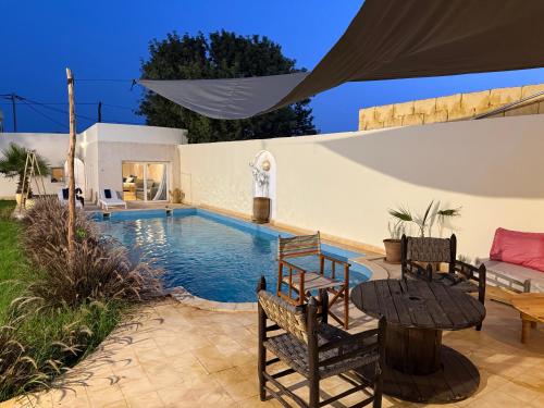 a patio with a table and chairs next to a swimming pool at Serenity Mogador in Essaouira