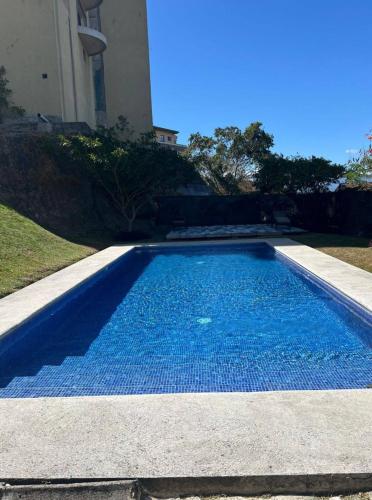 a swimming pool with blue water in front of a building at Nice and confortable 2 bedrooms apartment in Escazu in San Antonio
