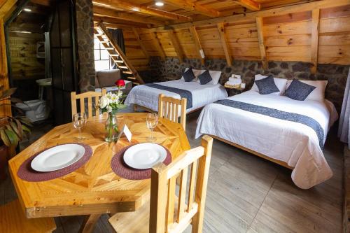 a room with two beds and a wooden table with a dining room at Bosque de Perlillas in Mexico City