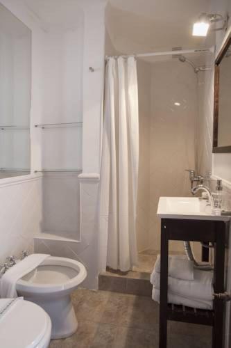 a white bathroom with a toilet and a sink at Del Prado in San Carlos de Bariloche
