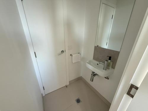 a white bathroom with a sink and a mirror at 5min Walk to Lift 3BR Luxe Chalet with Views & Fire in Mount Buller