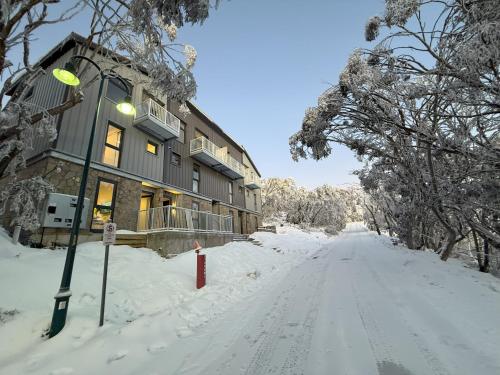 a snow covered road in front of a building at 5min Walk to Lift 3BR Luxe Chalet with Views & Fire in Mount Buller