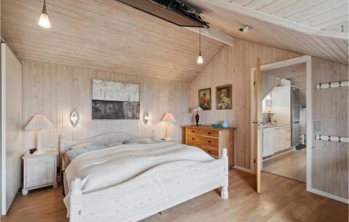 a bedroom with a white bed and a wooden wall at 3 Bedroom Cozy Home In Løgstør in Løgsted