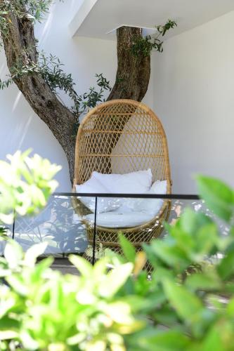 a rattan chair and a glass table in front of a tree at Luna Mare Boutique Seaside in Borsh