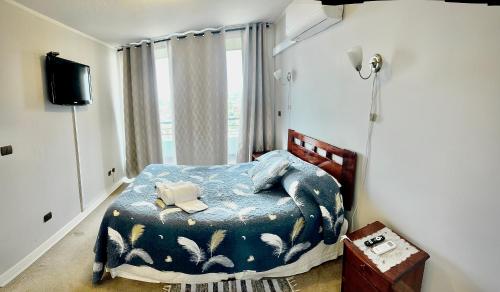 1 dormitorio con 1 cama con edredón azul y TV en Apartamento Vista Buena, en Talca