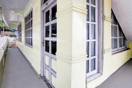 a white building with windows on a street at Super Hotel O Ghoom Formerly Aps Homestay in Darjeeling