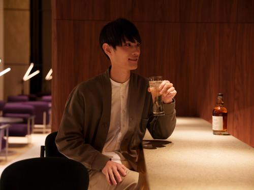 a young man sitting on the floor with a drink at CROSS Life Hakata Tenjin in Fukuoka