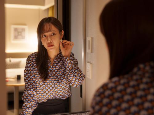 a woman brushing her teeth in front of a mirror at CROSS Life Hakata Tenjin in Fukuoka