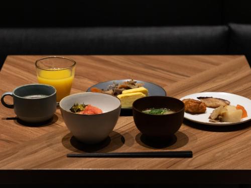 a table with bowls of food and a glass of orange juice at CROSS Life Hakata Tenjin in Fukuoka
