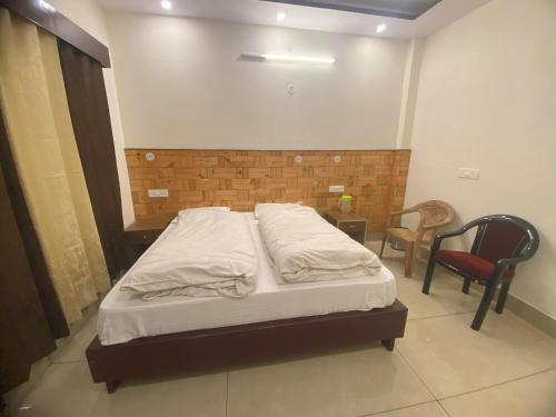 a bedroom with a bed and a chair in it at Hotel Kailash in Harsil