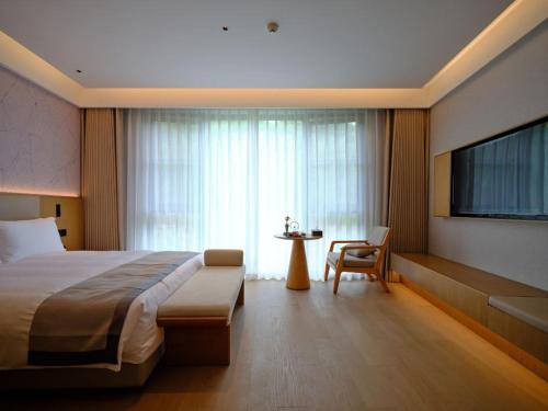 a hotel room with a large bed and a television at Ruolinqiao Valley Garden Hotel in Tiantai