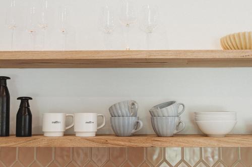 a shelf with cups and plates and wine glasses at Private & Stylish Hinterland Cottage in Gold Coast