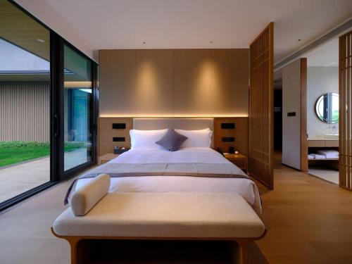 a large bedroom with a large bed and large windows at Ruolinqiao Valley Garden Hotel in Tiantai