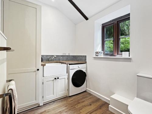 a white laundry room with a washer and dryer at Byre Cottage Dulverton in Dulverton