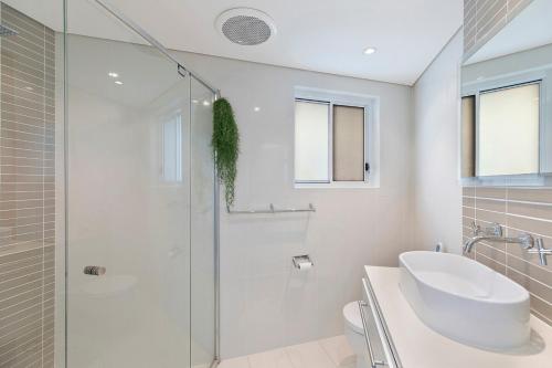 Un baño blanco con ducha y lavabo. en Skywater Retreat - 3 bedroom, en The Entrance