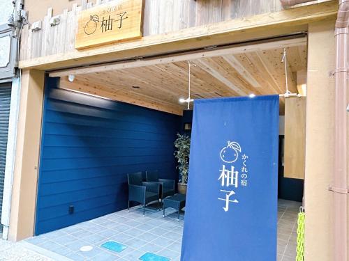 eine blaue Garagentür mit Stühlen davor in der Unterkunft かくれの宿 柚子 in Onomichi