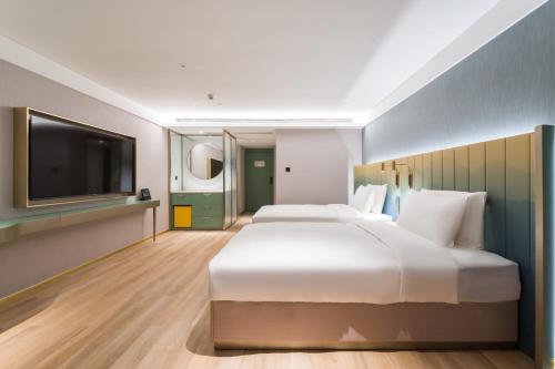 a bedroom with a large bed and a flat screen tv at Manxin Hotel Guangzhou Baiyun Airport Branch in Guangzhou