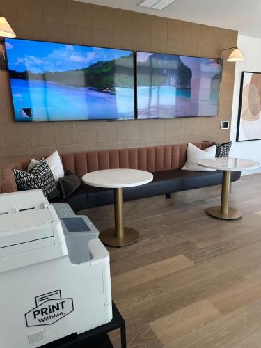 a waiting room with two tables and a large screen at Pink Couture in Austin