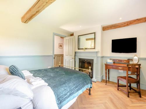 a bedroom with a bed and a desk and a tv at The Coach House in Longtown