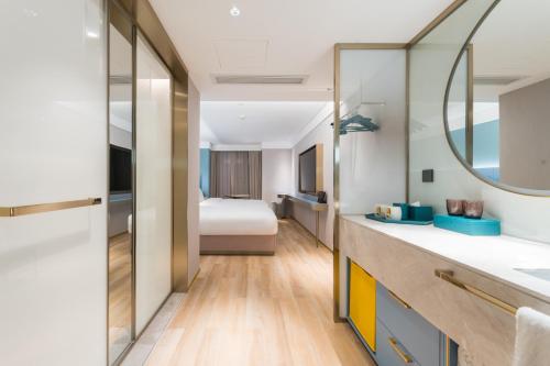 a bathroom with a bed and a sink and a mirror at Manxin Hotel Guangzhou Baiyun Airport Branch in Guangzhou