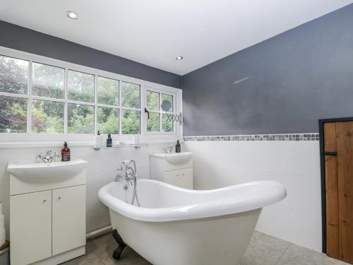 a bathroom with a white tub and two sinks at Woods Cottage in Usk