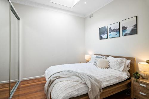 a bedroom with a bed with white walls at Port Melbourne Victorian Cottage in Melbourne