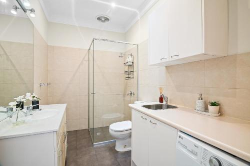 a bathroom with a toilet and a sink and a shower at Port Melbourne Victorian Cottage in Melbourne