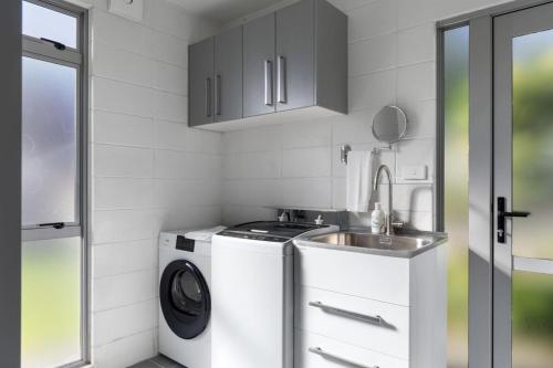 a kitchen with a washing machine and a sink at Modern 2BR Home in Gisborne