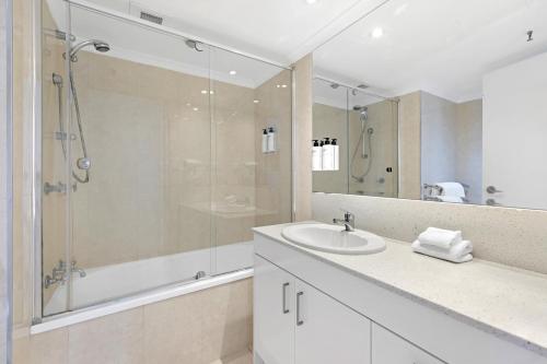 a white bathroom with a shower and a sink at ULTIQA Beach Haven on Broadbeach in Gold Coast